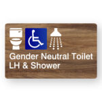 Gender Neutral Accessible Toilet LH & Shower Braille Sign in Mid-Tone Woodgrain Acrylic. A Mid-Tone Woodgrain panel with white raised tactile text & graphics including the Toilet, Accessible & Shower symbols.