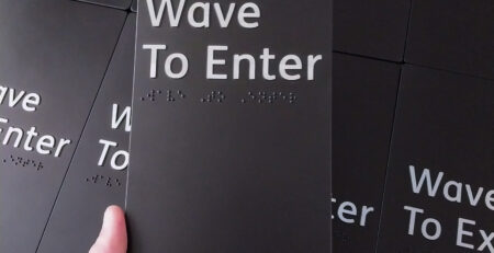 Person holding a wave to enter Braille Sign