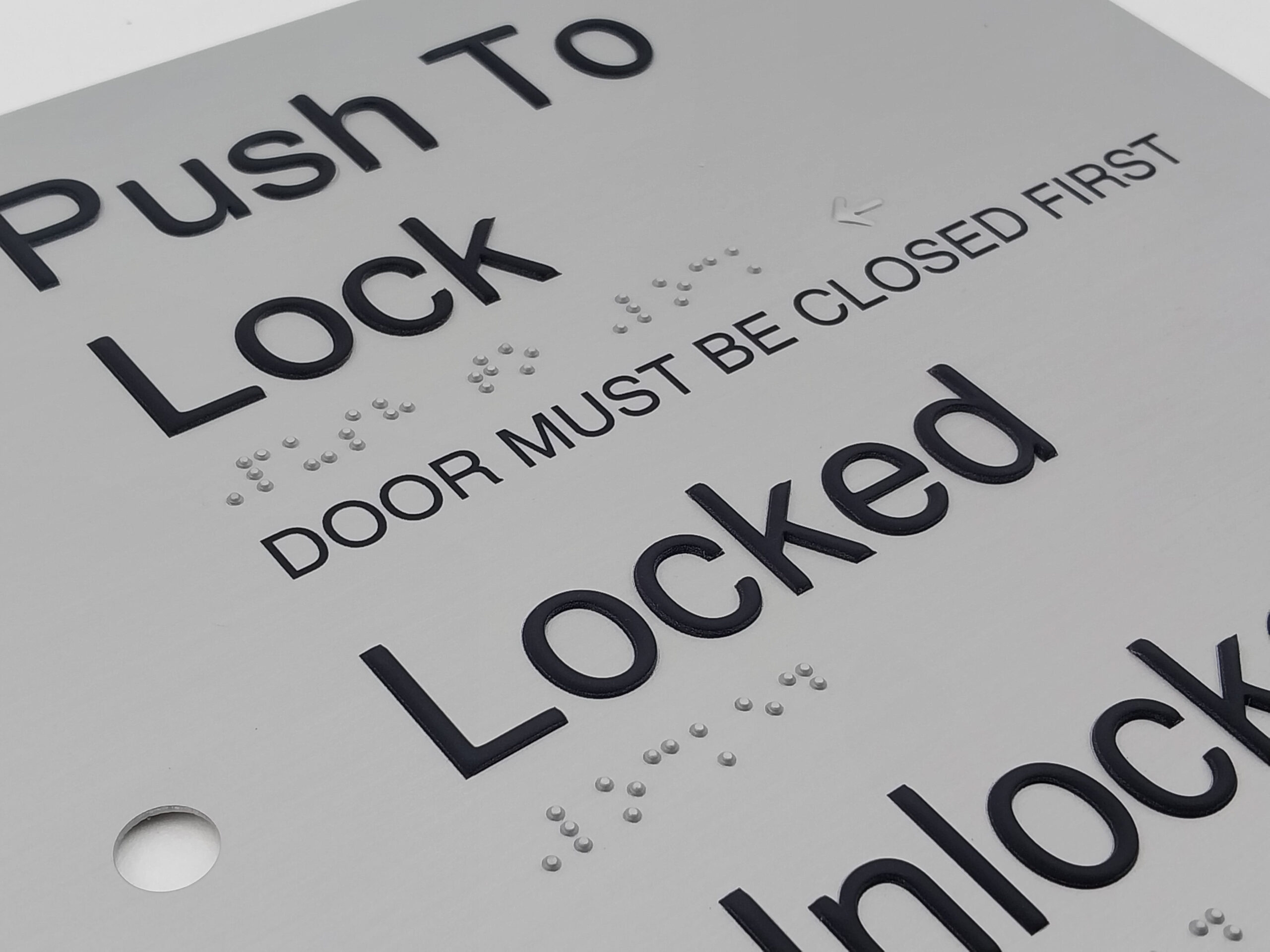 Push to Lock, Locked, Unlock Anodised Aluminium Braille Sign. Silver Sign panel with Black Raised text, Braille is Shown & Button hole cutouts