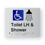 Accessible Toilet LH & Shower Braille Sign in Tactile Printed Silver Acrylic. Silver Sign panel with Blue & white Accessible Symbol, Black Shower Symbol. Black text reads Toilet LH & Shower. Black Braille text is shown