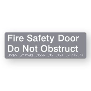 Fire Safety Door Do Not Obstruct Braille Sign in Tactile printed Grey Acrylic. Grey Sign panel with White Text that reads Fire Safety Door Do Not Obstruct. White Braille is shown